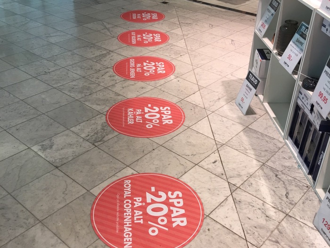 Runde gulvfolier med tilbudsbudskaber monteret på marmorgulv i butik