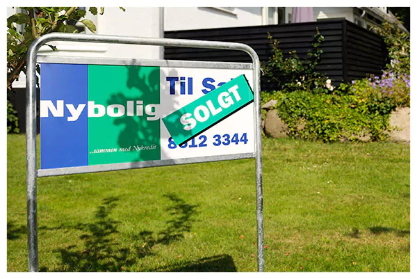 Klassisk mæglerskilt på stativ foran villa med Til salg-budskab