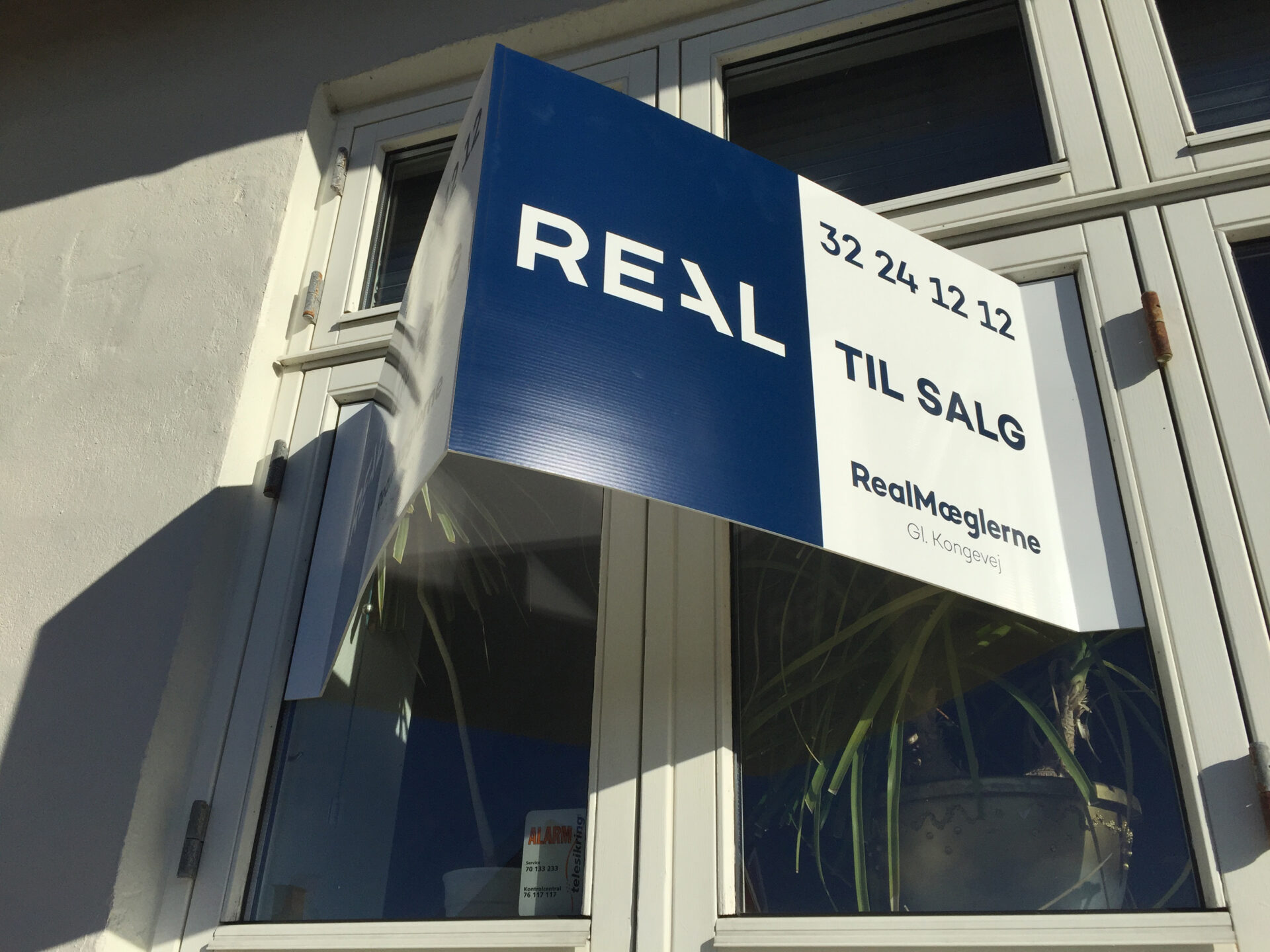 Vinkelmonteret mæglerskilt med Til salg på facade